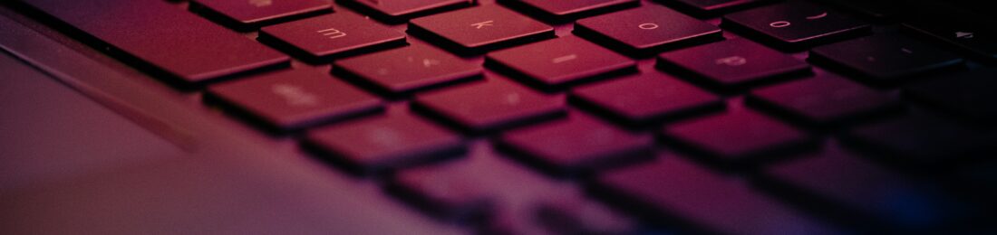 Close-up of a laptop keyboard with red and blue ambient lighting